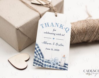 May include: A baby shower thank you tag with the text "THANK-Q for celebrating with us!" and the names Allison & Dustin, June 21, 2025. The tag features a blue gingham pattern, baby shoes, and a bottle. A wrapped gift and twine are in the background.