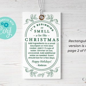 May include: A white tag with green holly leaves and a green circle around the text "It's beginning to smell - a lot like - Christmas". The text inside the circle says "Add ingredients to a small saucepan or mini slow cooker. Add 2-3 cups of water. Simmer on low, uncovered. Add additional water as needed. Scent should last for a few days. Happy Holidays! - Kathryn".