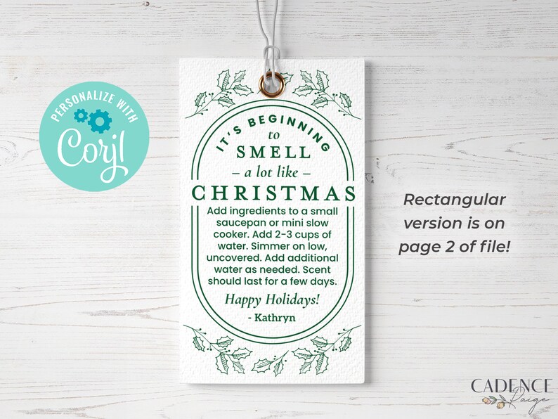 May include: A white tag with green holly leaves and a green circle around the text "It's beginning to smell - a lot like - Christmas". The text inside the circle says "Add ingredients to a small saucepan or mini slow cooker. Add 2-3 cups of water. Simmer on low, uncovered. Add additional water as needed. Scent should last for a few days. Happy Holidays! - Kathryn".
