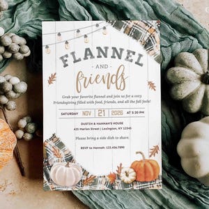 May include: A rectangular invitation card featuring a white wood-plank background with string lights and plaid fabric accents. The text reads Flannel and Friends, with event details for Saturday, Nov 21, 2026, at 5:30 PM at Dustin and Hannah's house.