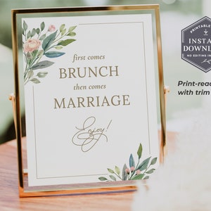 May include: A printable sign with a floral design and the text "first comes brunch then comes marriage enjoy!"  The sign is in a gold frame and is sitting on a wooden table.  The sign is a print-ready PDF with trim marks.