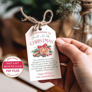 Puede incluir: Una etiqueta de regalo blanca con tem&aacute;tica navide&ntilde;a con el texto "It's Beginning to Smell a lot like Christmas". La etiqueta presenta ilustraciones de palitos de canela, una rodaja de naranja y un lazo rojo. La etiqueta est&aacute; atada con hilo.