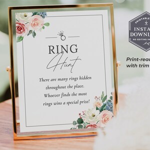 May include: A printable sign with a floral design in shades of pink, blue, and green. The sign says "RING Hunt" and includes instructions for a ring hunt game. The text says "There are many rings hidden throughout the place. Whoever finds the most rings wins a special prize!"