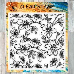 以下が含まれることがあります： 花と葉の黒い線画が特徴の、フローラルデザインのクリアスタンプ。「CLEAR STAMP PHOTOPOLYMER」とラベルされています。背景はカラフルな抽象的なデザインです。