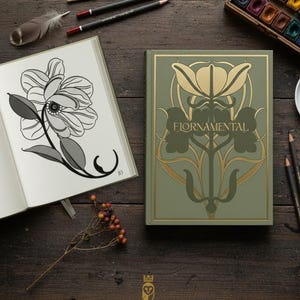 Puede incluir: Un cuaderno de bocetos abierto con una ilustración floral en blanco y negro junto a un libro verde con arte floral dorado y la palabra "FIORNAMENTAL". Lápices, un pincel y acuarelas están dispuestos sobre una superficie de madera oscura.