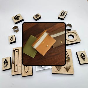 May include: An assortment of leather wallets in green, tan, and brown, alongside various wooden craft tools and metal rings. The wallets are open, showcasing their interior design. The wooden tools feature leaf and geometric cutouts.