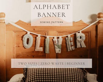 以下が含まれることがあります： 木製のヘッドボードに飾られた、手作りのアルファベットバナー「OLIVER」。 各布文字は、ストライプやチェックなど、ユニークなパターンを持っています。 バナーは縫製パターンの一部で、「TWO SIZES | ZERO WASTE | BEGINNER」というテキストが表示されています。