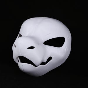May include: A white, 3D-printed mask with an animalistic design. It has large eye openings, a pronounced snout, and a partially open mouth. The surface shows print lines, indicating a textured finish. This mask is suitable for cosplay or costume events.