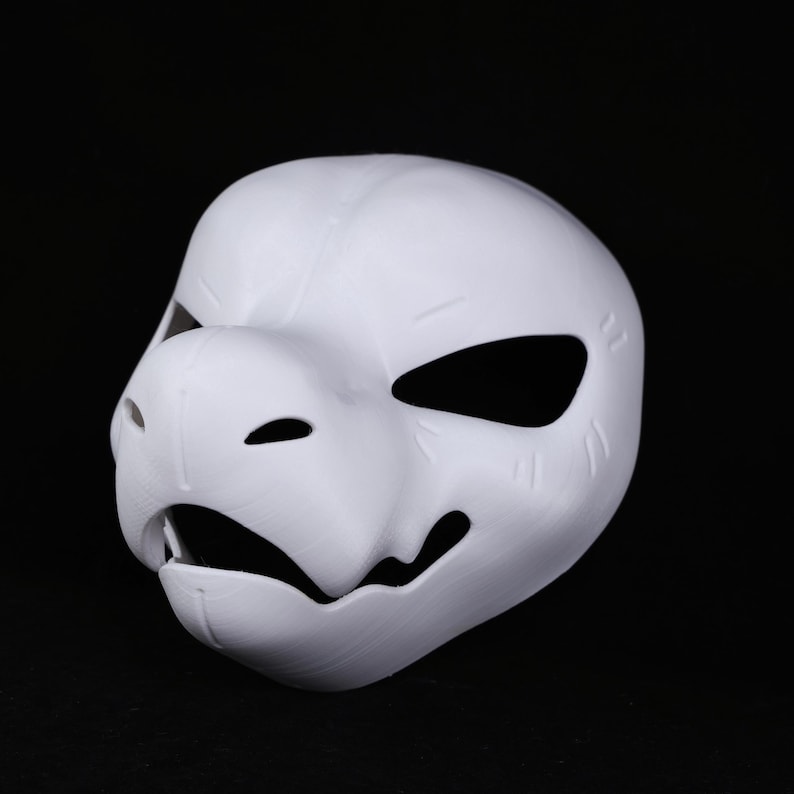 May include: A white, 3D-printed mask with an animalistic design. It has large eye openings, a pronounced snout, and a partially open mouth. The surface shows print lines, indicating a textured finish. This mask is suitable for cosplay or costume events.