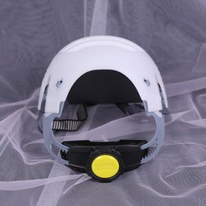 May include: White safety helmet with a black and yellow adjustment dial. The helmet has a gray suspension system and a black and white adjustable strap. The helmet is designed to protect the head from impact.