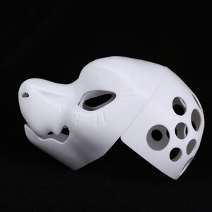 May include: A white, 3D-printed mask with a canine-like snout and eye openings. The mask features several circular ventilation holes on the side and vertical lines on the snout. The mask is designed for cosplay or costume use.
