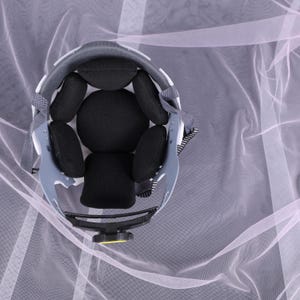May include: An overhead view of a gray and white helmet with black padding. The helmet has a black adjustment knob and gray straps. The interior padding is black and designed for comfort. The helmet is designed for safety and protection.