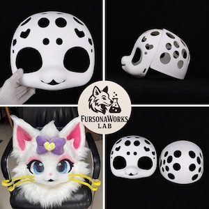 May include: White fursuit head base with black spots and large eye openings. The head has a cat-like design with a smiling mouth. The image also shows a completed fursuit head with pink ears, blue eyes, and a purple bow. The logo "FursonaWorks LAB" is also visible.