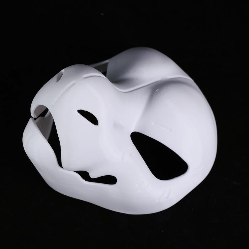 May include: A white plastic mask with eye and mouth cutouts. The mask has a smooth, curved design and is intended to cover the face. It is likely for costume or theatrical purposes.