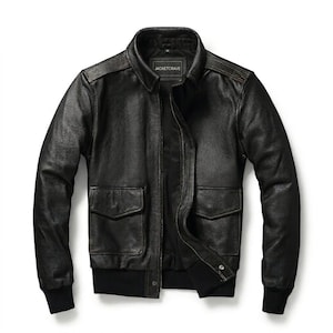 Peut inclure: Un blouson aviateur en cuir noir doté d'un col classique, d'une fermeture éclair frontale et de deux grandes poches à rabat sur le devant. L'étiquette intérieure porte le texte JACKETCRAVE. Le blouson possède des poignets et un ourlet côtelés.