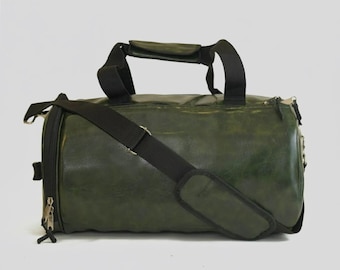 May include: A dark green duffel bag with a black shoulder strap and handles. The bag has a cylindrical shape with a zip closure and a padded shoulder strap for comfortable carrying. The bag is made of a durable material.