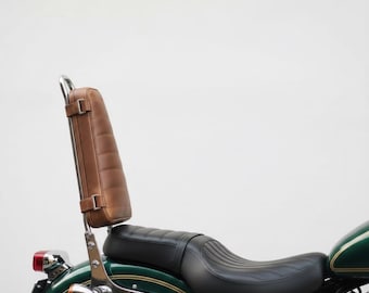 May include: A brown leather motorcycle backrest with a padded design and chrome supports. The backrest is attached to a black motorcycle seat and a green and gold motorcycle body.