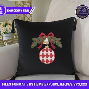 Puede incluir: Cojín cuadrado negro con un diseño de adorno navideño. El adorno es rojo y blanco con un patrón de diamantes, una campana dorada y un lazo rojo. El cojín tiene borlas negras en cada esquina. El texto "EMBROIDERY FILES" es visible.