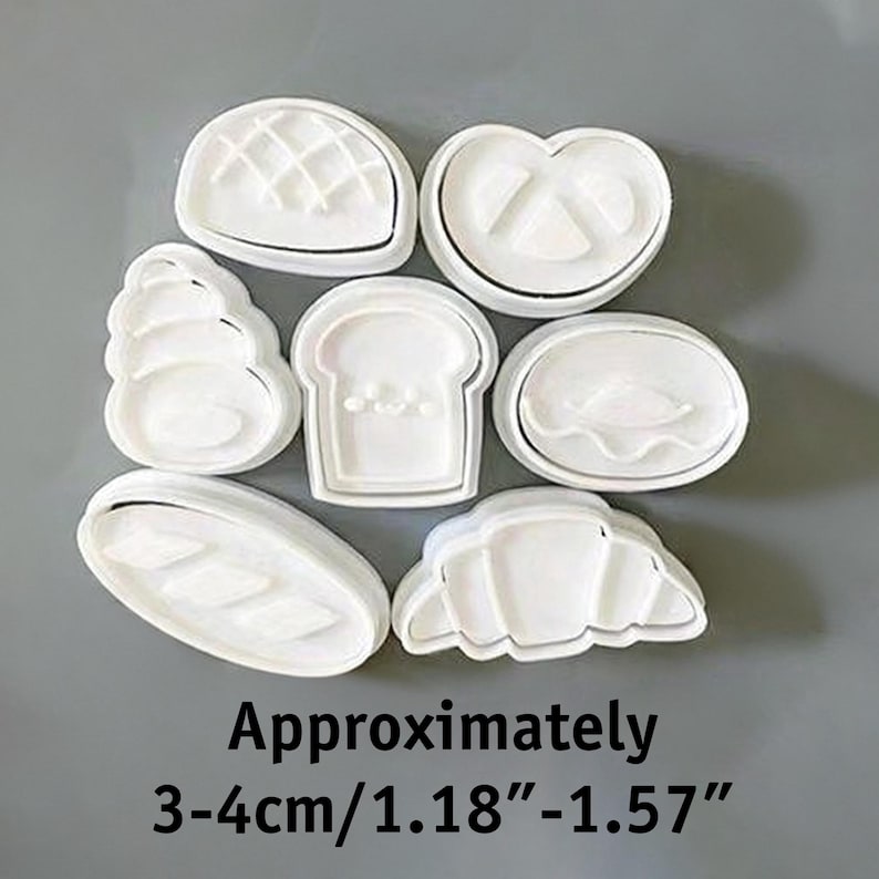 May include: A set of white plastic cookie cutters in various bread shapes, including a pretzel, croissant, and loaf of bread. The text "Approximately 3-4cm/1.18"-1.57"" is displayed below the cutters.