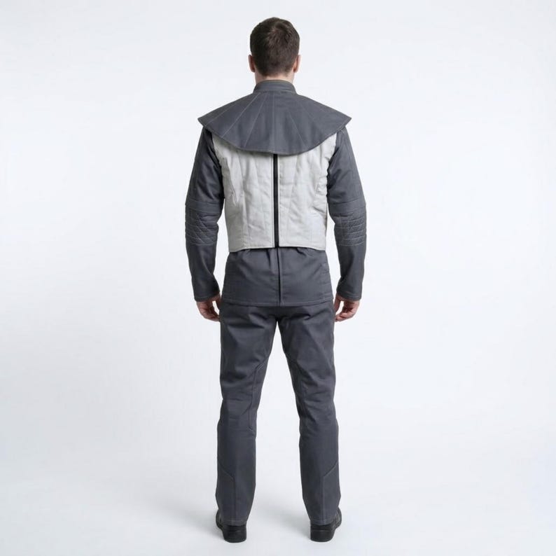 Może przedstawiać: Szary mundur składający się z kurtki z kołnierzem w kształcie peleryny, jasnoszarej kamizelki, koszuli z długim rękawem i pasujących spodni. Osoba jest widziana od tyłu, prezentując design i dopasowanie stroju.