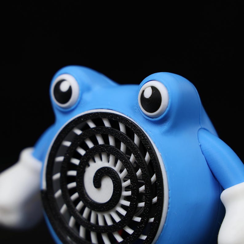 Pode incluir: Figura azul de um personagem de desenho animado com olhos grandes e redondos e luvas brancas. O personagem tem um design de espiral branco e preto no peito. A figura est&aacute; em um fundo preto.