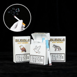 Puede incluir: Sopladores de burbujas blancos con forma de cigarrillo con el texto "BUBBLE JUST KIDDING" y "NOT FOR SMOKING JUST FOR FUN!!!!" en las cajas. Cada caja presenta un animal pixelado diferente: un águila, una paloma y un lobo.