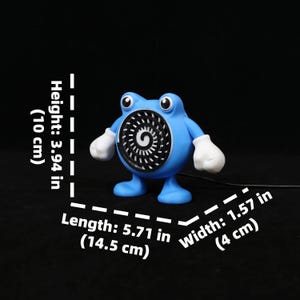 Pode incluir: Uma figura azul, semelhante a um desenho animado, com um centro com padr&atilde;o espiral. A figura tem luvas e p&eacute;s brancos e mede 10 cm de altura, 14,5 cm de comprimento e 4 cm de largura.