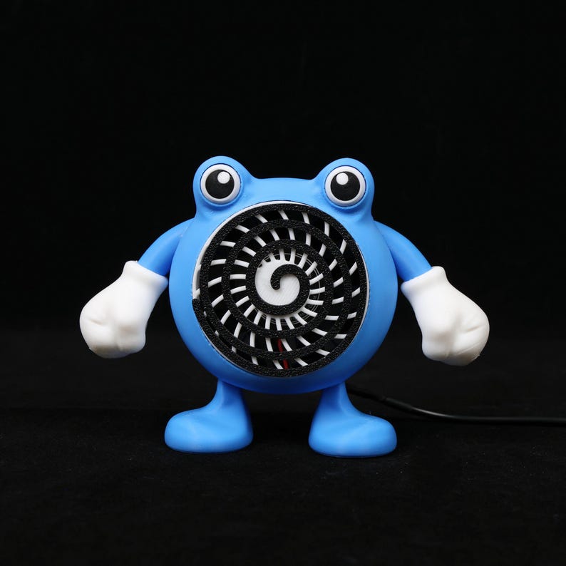 Pode incluir: Um ventilador azul, semelhante a um desenho animado, com luvas e p&eacute;s brancos. O ventilador tem um design em espiral no centro e olhos grandes e redondos. O ventilador est&aacute; ligado a um cabo preto.