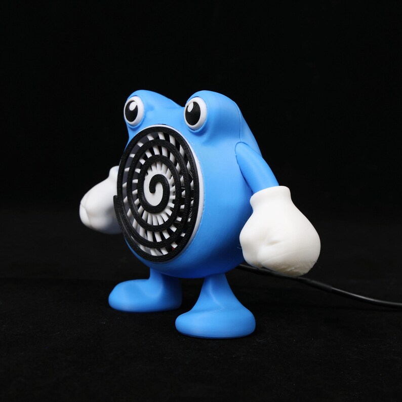 Pode incluir: Uma figura azul com luvas e p&eacute;s brancos, e olhos grandes em preto e branco. A figura tem um desenho em espiral no peito e um cabo preto que se estende da sua base. O design geral &eacute; de desenho animado.