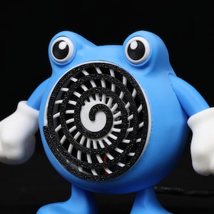 Pode incluir: Um personagem azul, semelhante a um desenho animado, com olhos grandes e luvas brancas. O personagem tem uma abertura circular no peito com um desenho em espiral preto. A figura est&aacute; em p&eacute; sobre duas pernas azuis.