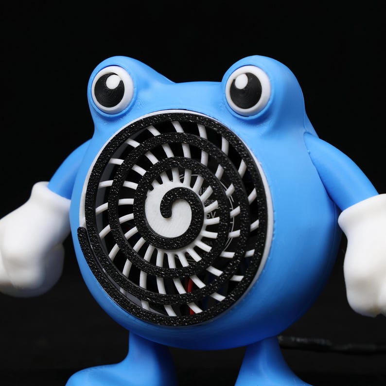 Pode incluir: Um personagem azul, semelhante a um desenho animado, com olhos grandes e luvas brancas. O personagem tem uma abertura circular no peito com um desenho em espiral preto. A figura est&aacute; em p&eacute; sobre duas pernas azuis.