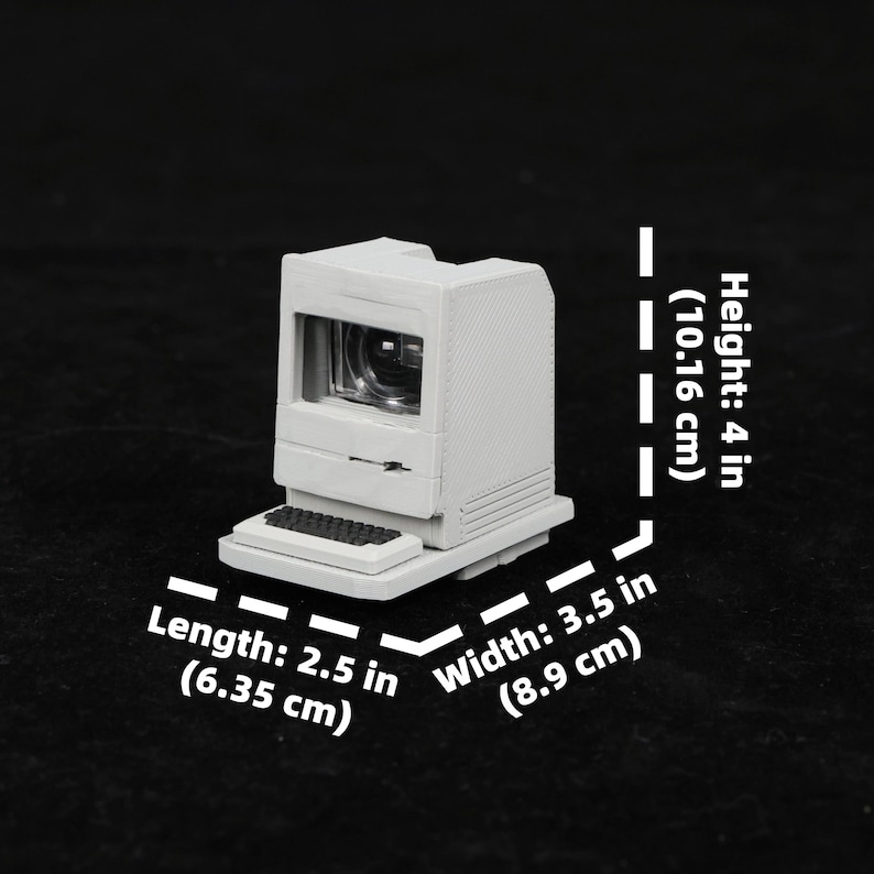 May include: A miniature, off-white computer model with a screen and keyboard. The model is 4 inches (10.16 cm) tall, 2.5 inches (6.35 cm) long, and 3.5 inches (8.9 cm) wide. The computer has a retro design.