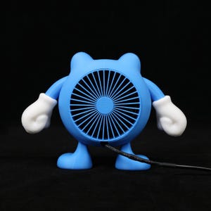 Pode incluir: Um ventilador azul de novidade em forma de personagem de desenho animado com um rosto de ventilador redondo, bra&ccedil;os, pernas e m&atilde;os enluvadas brancas. O ventilador tem um cabo de alimenta&ccedil;&atilde;o preto que se estende da parte inferior. O ventilador est&aacute; em um fundo preto.