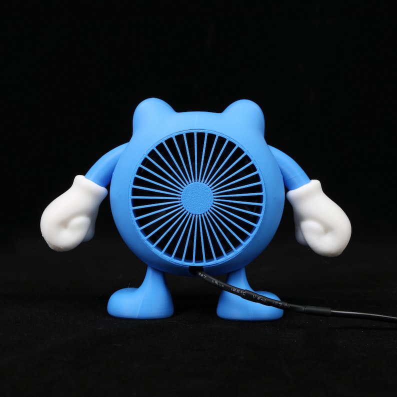 Pode incluir: Um ventilador azul de novidade em forma de personagem de desenho animado com um rosto de ventilador redondo, bra&ccedil;os, pernas e m&atilde;os enluvadas brancas. O ventilador tem um cabo de alimenta&ccedil;&atilde;o preto que se estende da parte inferior. O ventilador est&aacute; em um fundo preto.