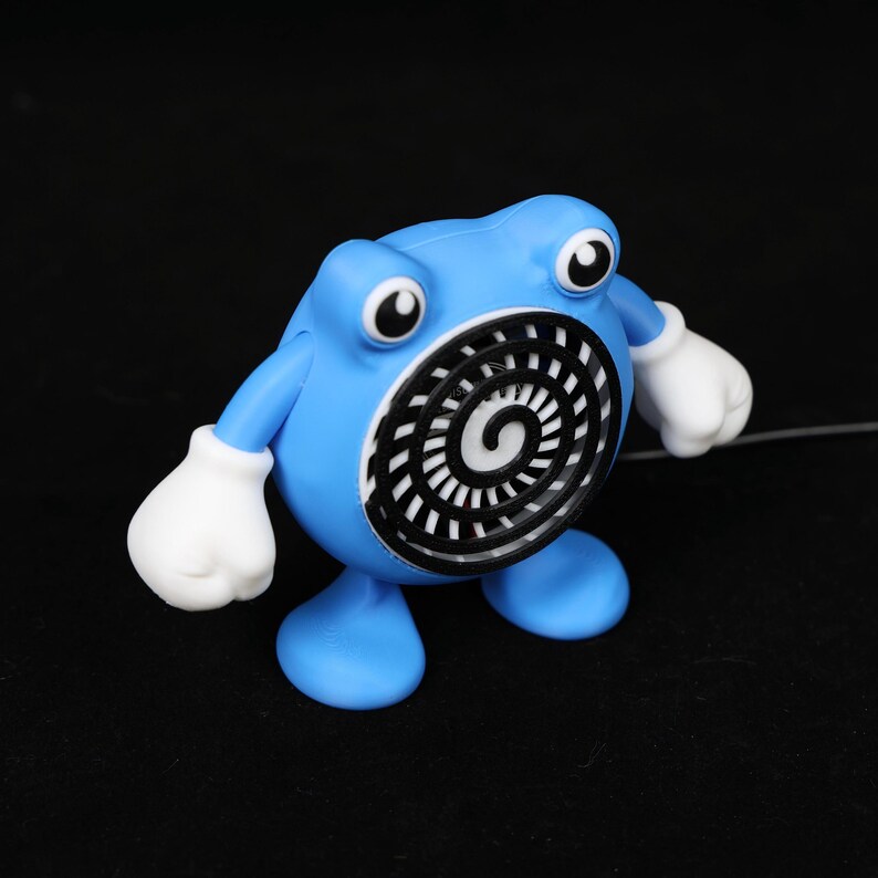 Pode incluir: Uma figura azul com luvas e olhos brancos. A figura tem um desenho em espiral preto e branco na barriga. A figura est&aacute; em p&eacute; sobre dois p&eacute;s azuis e tem dois bra&ccedil;os. O fundo &eacute; preto.
