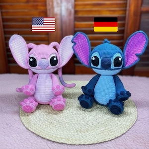 Könnte beinhalten: Zwei gehäkelte Plüschtiere, eines rosa und eines blau, die Zeichentrickfiguren ähneln. Das rosa Spielzeug hat große Ohren und einen langen Schwanz. Das blaue Spielzeug hat große Ohren und einen runden Körper. Beide Spielzeuge haben große schwarze Augen.