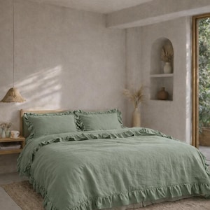 May include: A sage green bed set with frilled edges, including a duvet cover and two pillowcases, sits on a wooden bed frame. The bedroom features a neutral colour palette, a woven rug, and a hanging pendant light. The room has a natural, airy feel.