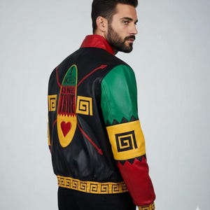 May include: Black leather jacket with red, green, and yellow detailing. The back displays the text "WORLD ONE TRIBE" with a heart and geometric patterns. The jacket has a red collar and cuffs, and green and yellow sleeves.