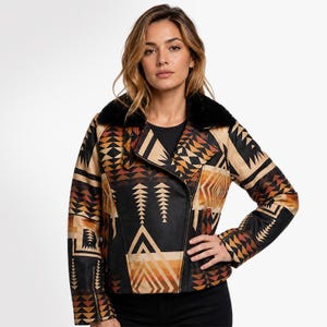 May include: A moto-style jacket featuring a geometric pattern in shades of black, tan, and burnt orange. The jacket has a black faux fur collar, an asymmetrical front zipper closure, and long sleeves with zippered cuffs, showcasing a bold print.
