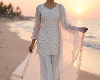 May include: A white embroidered tunic and palazzo trousers with a sheer scarf. The outfit has gold embroidery and a scalloped neckline. The ensemble is suitable for a special occasion.