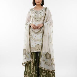 May include: White embroidered tunic and dupatta set with olive green palazzo trousers. The outfit features gold embroidery on the neckline, sleeves, and palazzo hems. The dupatta has floral patterns.