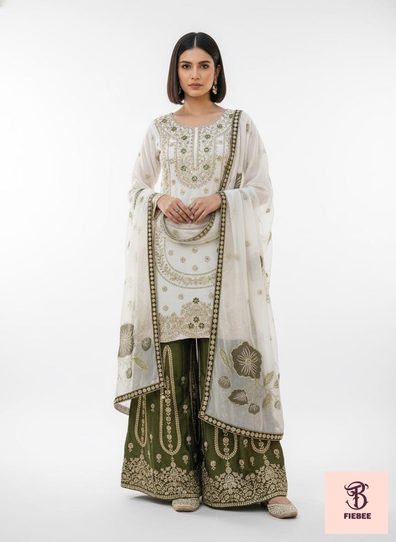 May include: White embroidered tunic and dupatta set with olive green palazzo trousers. The outfit features gold embroidery on the neckline, sleeves, and palazzo hems. The dupatta has floral patterns.