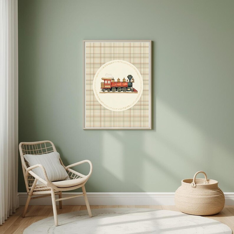 May include: A framed print featuring a vintage train illustration. The train is red and black, set against a cream-colored circle with a plaid background. The artwork is displayed on a light green wall, with a wicker chair and basket in the foreground.