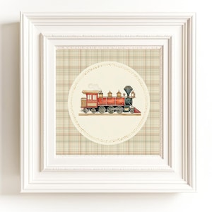 May include: A framed print featuring a vintage illustration of a red and black steam train. The train is set against a cream-colored circle with a dotted border, placed on a plaid background. The frame is white.