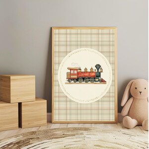 May include: A framed print featuring a vintage steam train illustration. The train is red, black, and gold, set against a cream-colored circle with a dotted border. The background is a plaid pattern in beige, brown, and red.