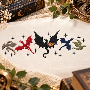 May include: A cream-colored fabric featuring an embroidered design of five dragons in gray, red, black with gold, blue, and green. The dragons are arranged in a horizontal row, interspersed with small black embroidered four-pointed stars.