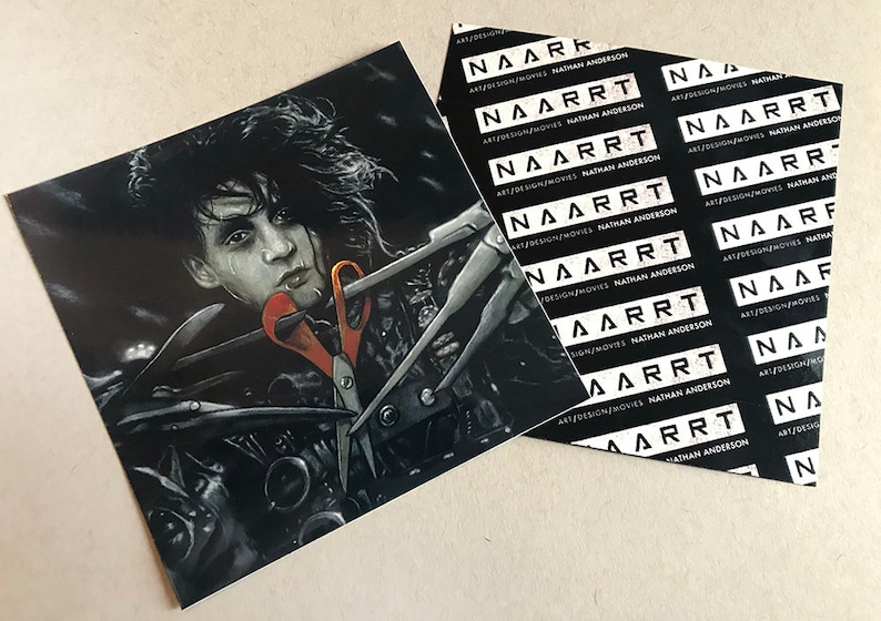 May include: A black and white illustration of a man with long black hair holding a pair of scissors. The image is printed on a sticker with the text "NAARRT ART/DESIGN/MOVIES NATHAN ANDERSON" repeated multiple times.