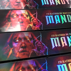 May include: Three iridescent stickers with the text "I'd rather be watching Mandy" and a graphic of a man with glowing eyes and a red background.