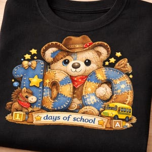 Peut inclure: T-shirt noir avec un ours de dessin animé portant un chapeau de cowboy, les chiffres "100" et un petit cheval. Le texte "days of school" est en dessous de l'ours. Le motif comprend des étoiles et un bus scolaire jaune.