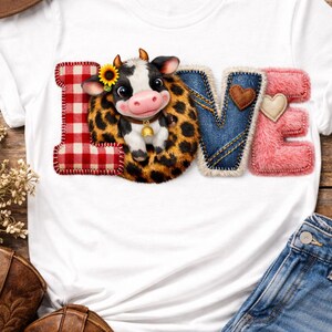 Peut inclure: T-shirt blanc avec le mot "LOVE" dans un design patchwork. Le "L" est en vichy rouge, le "O" est une vache avec un tournesol, le "V" est en jean et le "E" est en fausse fourrure rose. Bottes de cowboy et short en jean également visibles.